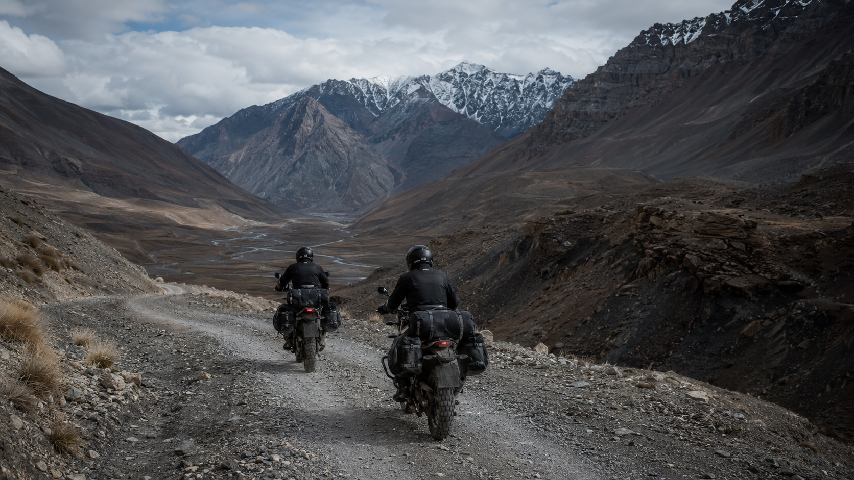 Dois motociclistas atravessando uma estrada remota entre montanhas